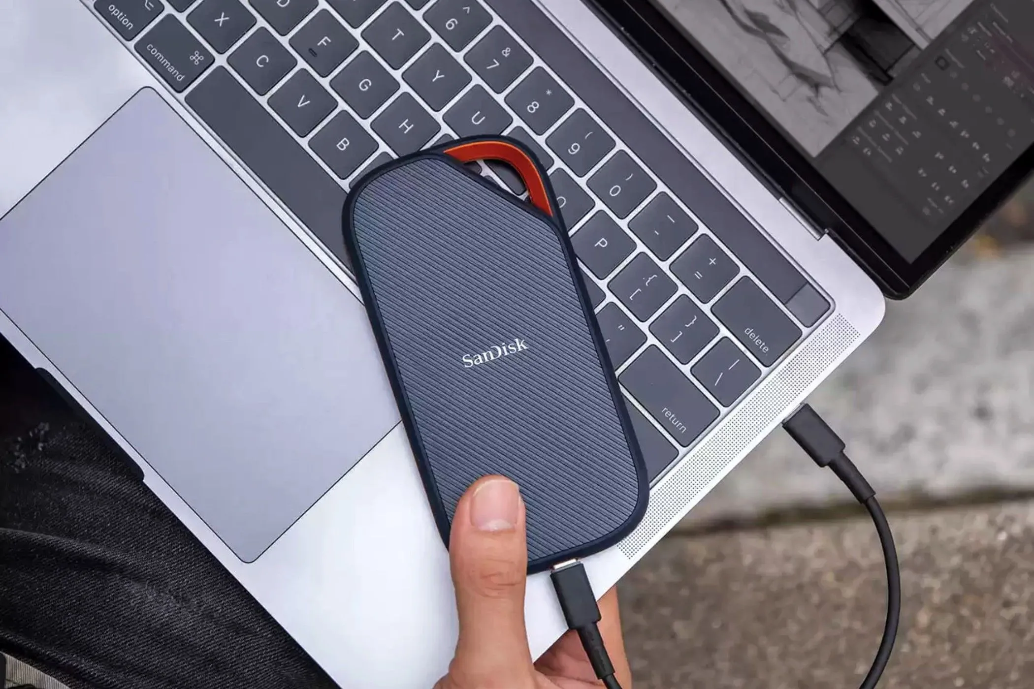 Ổ cứng SSD di động Sandisk Extreme Pro USB 4 màu đen trên bàn cạnh laptop, minh họa cho công nghệ lưu trữ hiệu suất cao.
