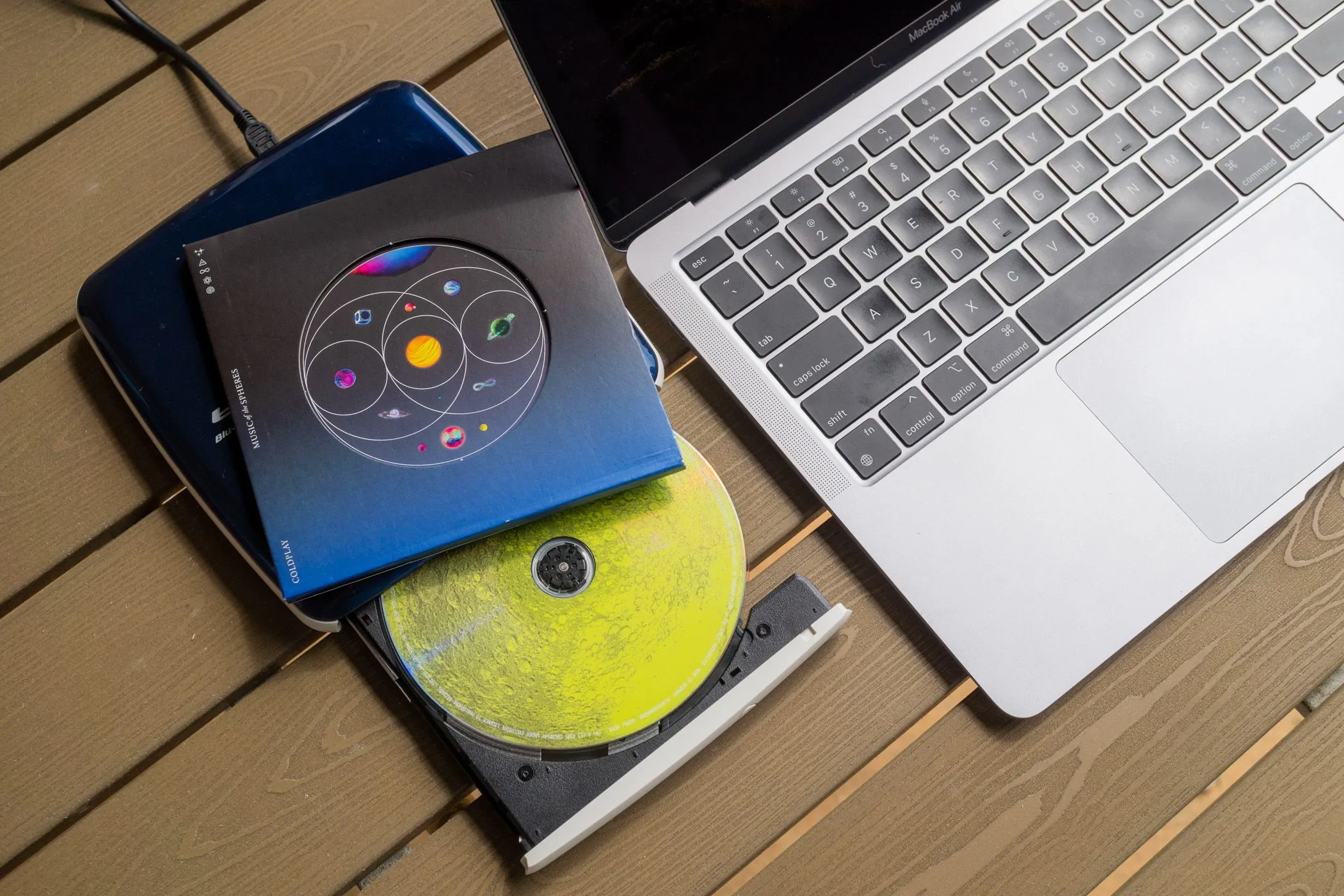Ổ đĩa CD gắn ngoài và đĩa nhạc CD bên cạnh MacBook Air