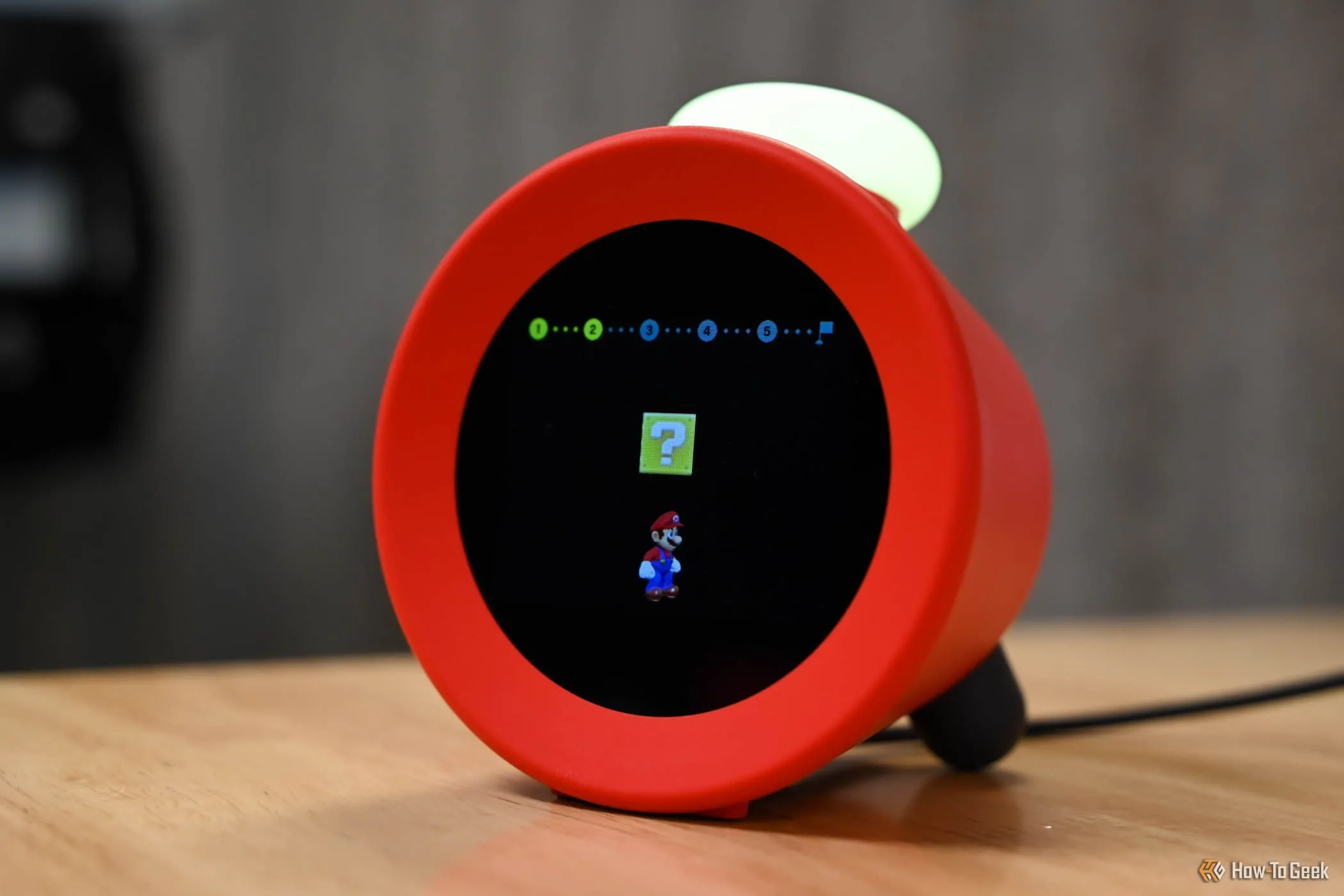 Quá trình thiết lập Nintendo Alarmo, hiển thị bàn tay đang chạm vào màn hình cảm ứng của đồng hồ.