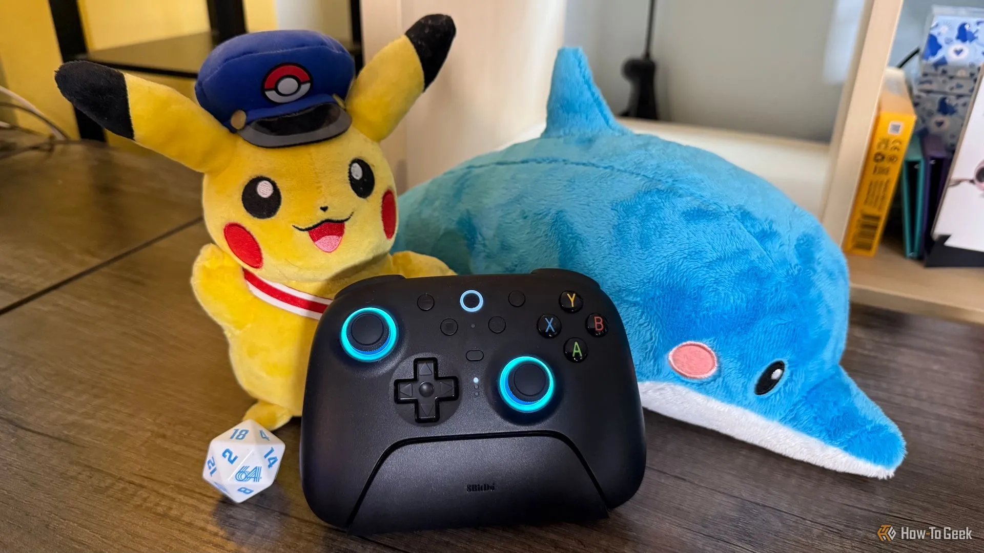 Tay cầm 8BitDo Ultimate 2 Wireless đặt trên đế sạc cùng các vật phẩm gaming trang trí