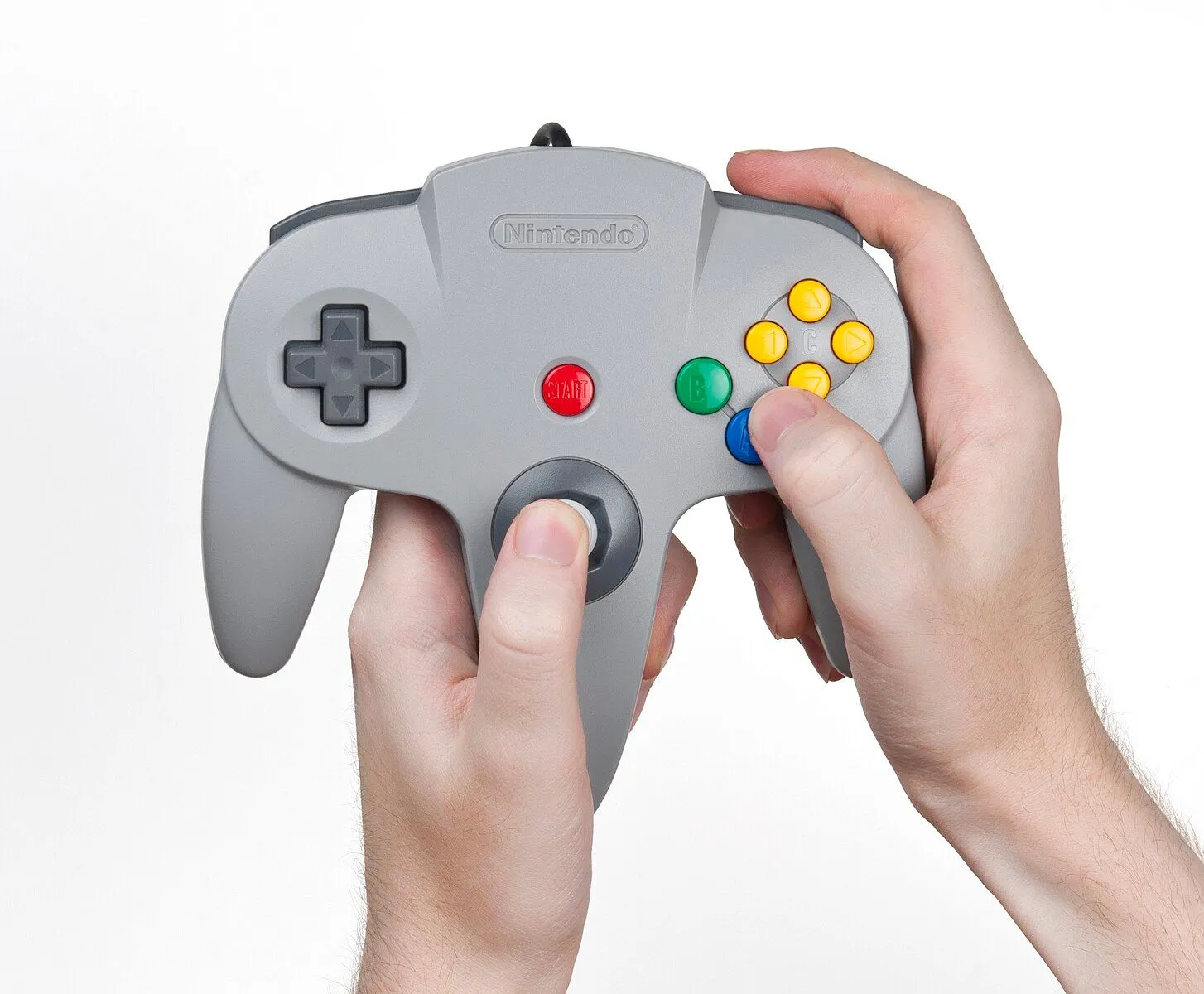 Tay cầm Nintendo 64 hình trident cầm trên tay, cho thấy thiết kế ba chạc độc đáo.