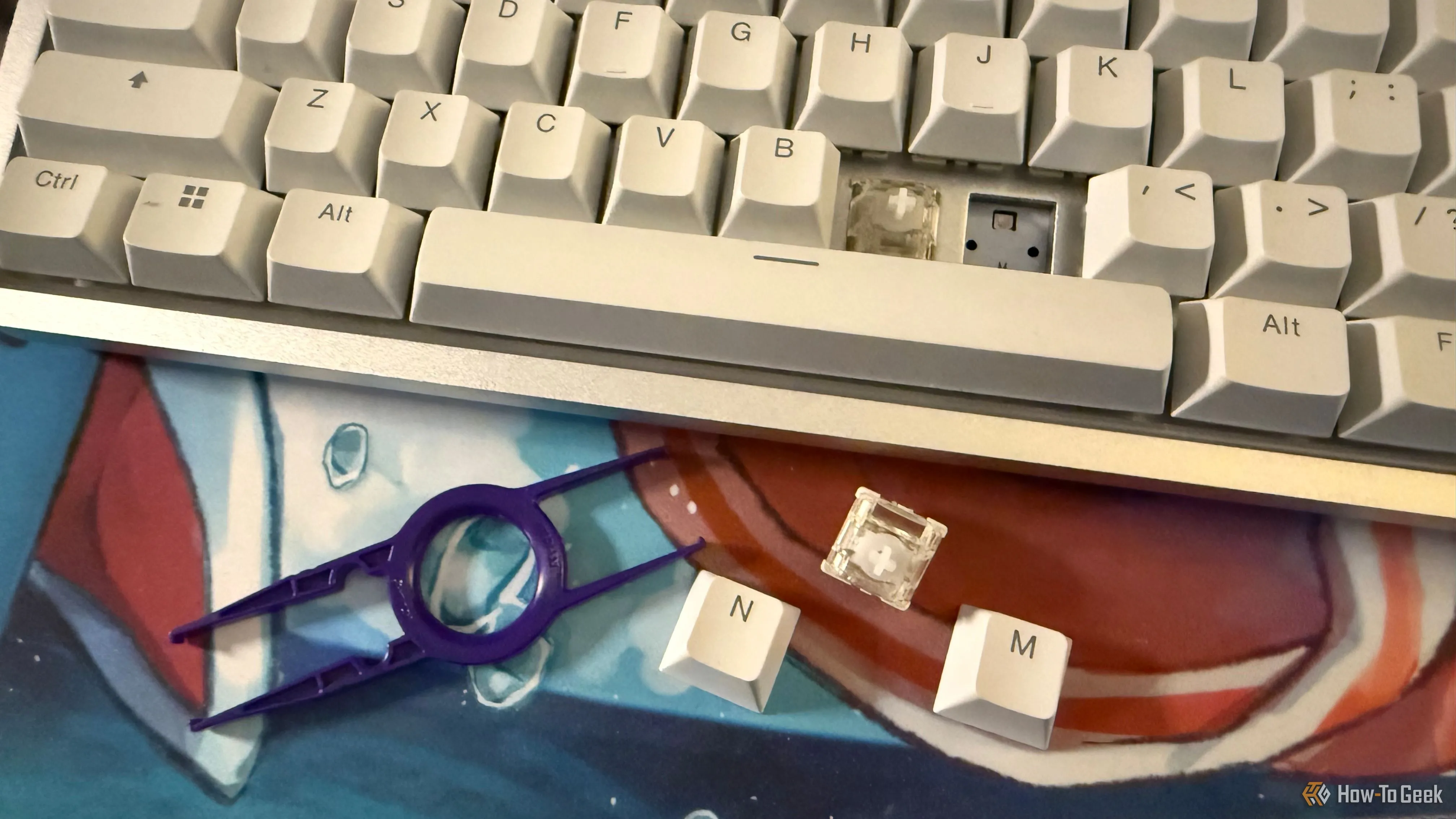 Bàn phím NZXT Function Elite MiniTKL với keycap và switch từ tính đã được tháo rời, cùng với dụng cụ gắp keycap và switch, minh họa khả năng tùy biến của bàn phím cơ.