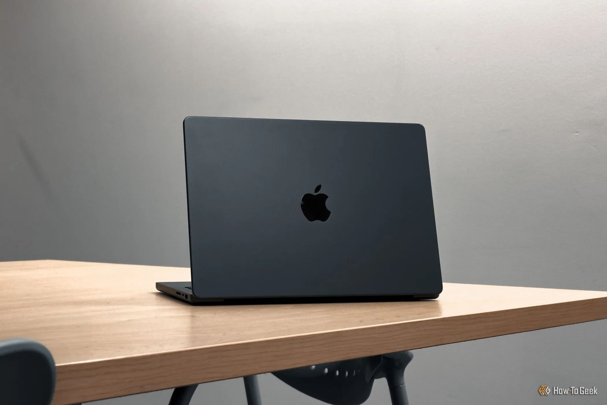 Mặt lưng MacBook Pro M4 đặt trên bàn gỗ, thể hiện tính di động